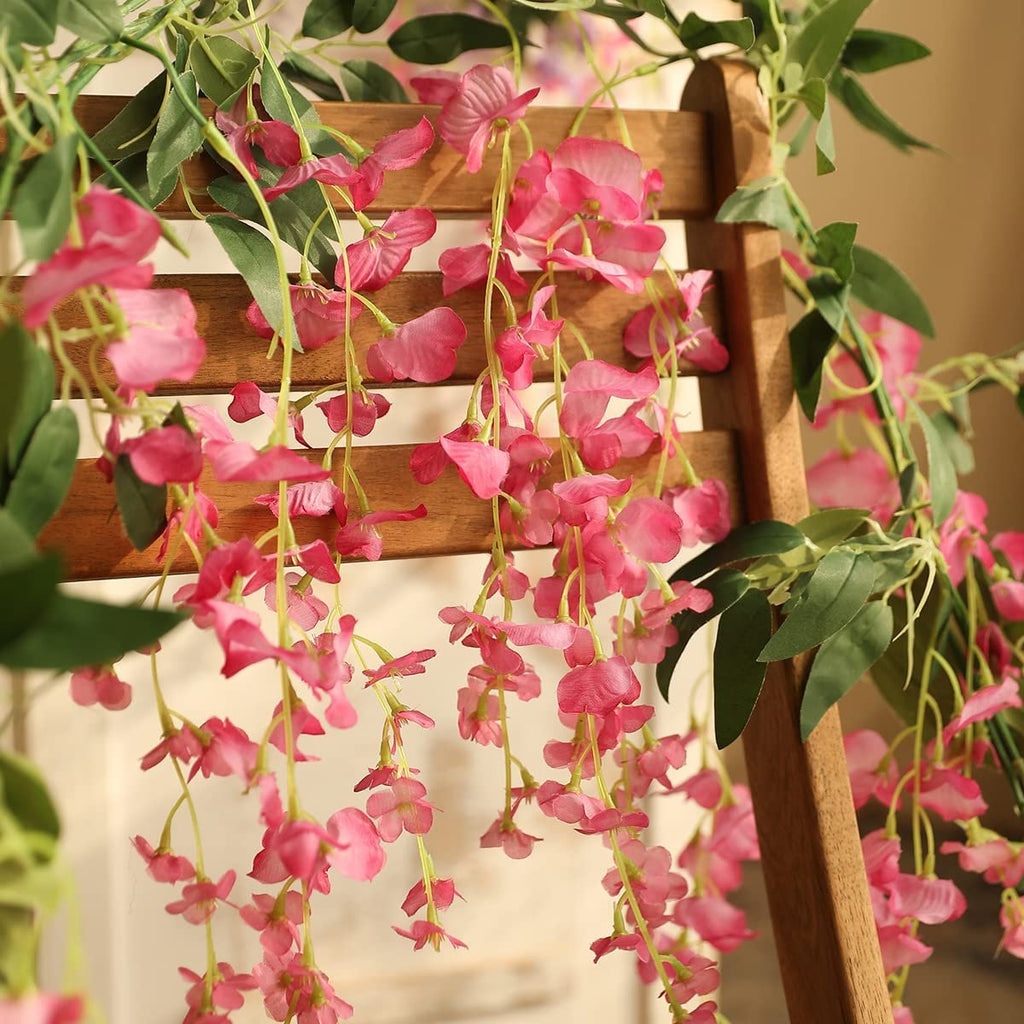 Artificial fuchsia wisteria garlands draped over a wooden chair back