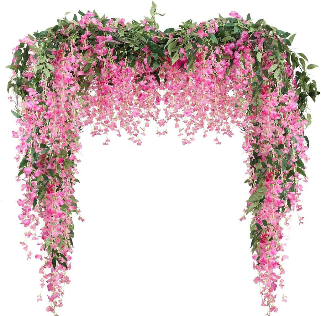 Artificial fuchsia wisteria garland with green leaves draped in an arch shape against a white background.