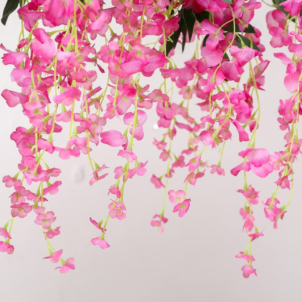 Close-up of cascading fuchsia artificial wisteria flower garlands against a light background.