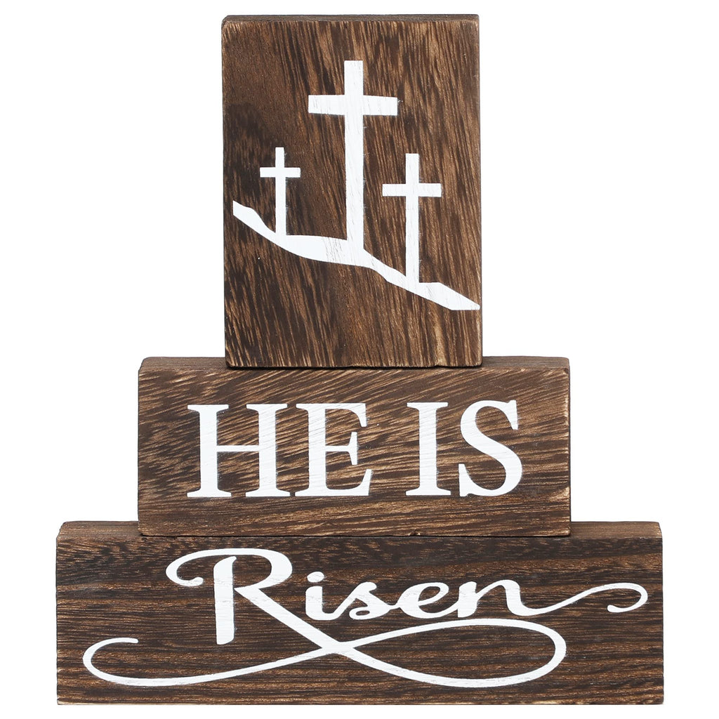 Three stacked wooden blocks with Christian Easter message 'HE IS Risen' and three crosses on the top block.