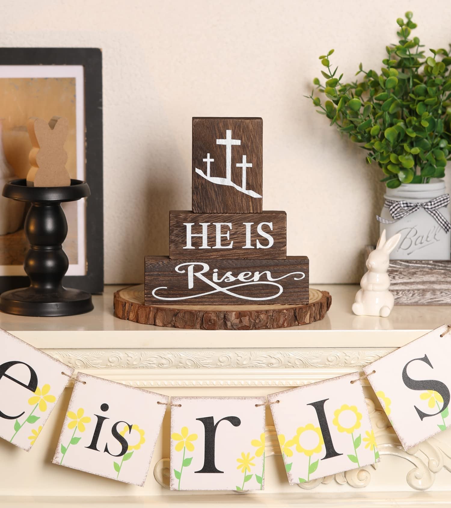 Stack of three wooden blocks with Christian Easter message 'HE IS Risen' and crosses, displayed on a rustic wood slice base.