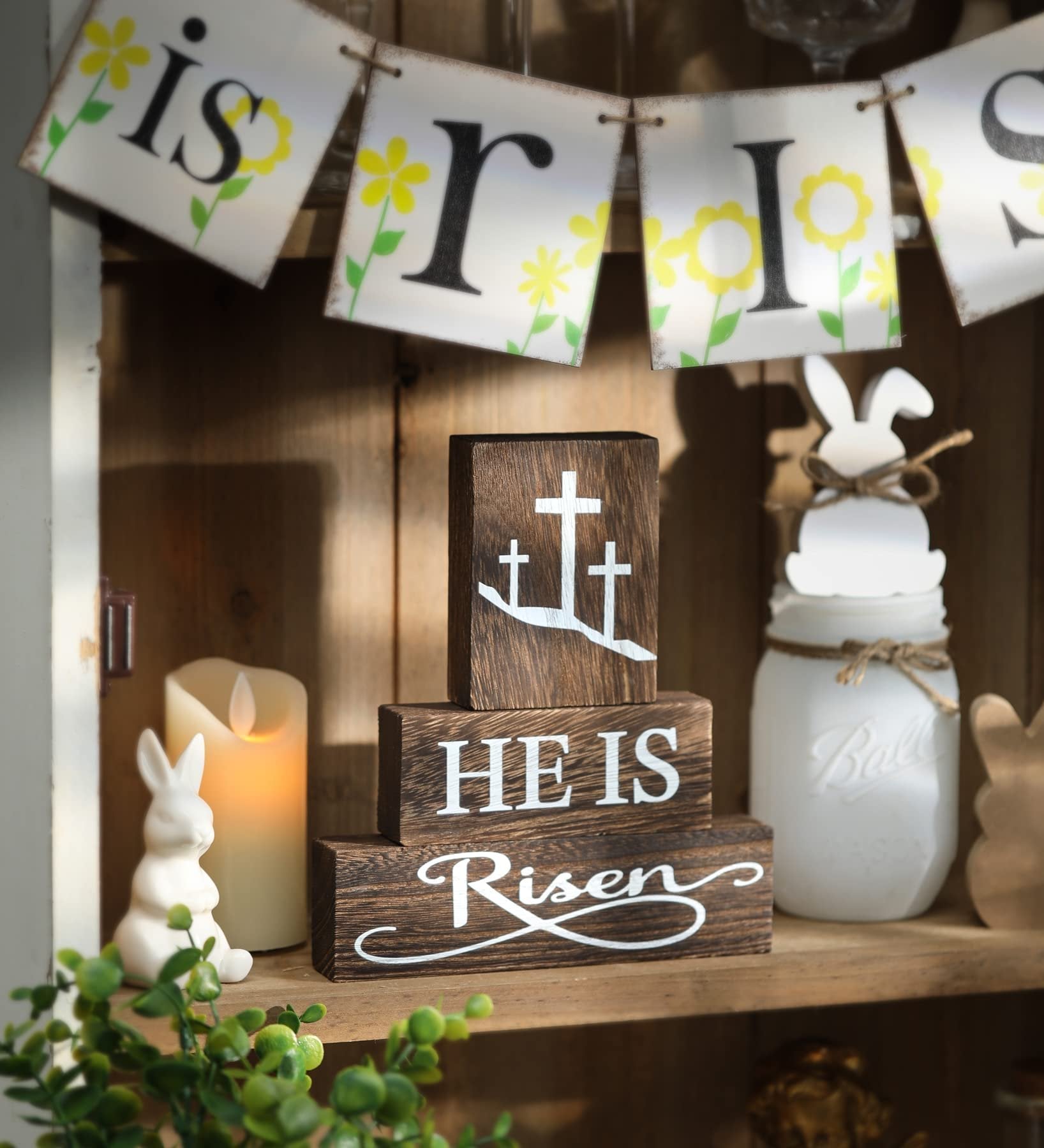 Stack of three wooden blocks with Easter messages and crosses, next to a candle and bunny decor.