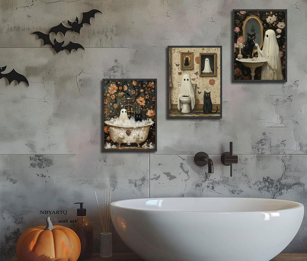 Three Halloween-themed canvas art prints featuring ghosts and black cats displayed on a textured wall above a bathtub. A carved pumpkin sits on the counter.