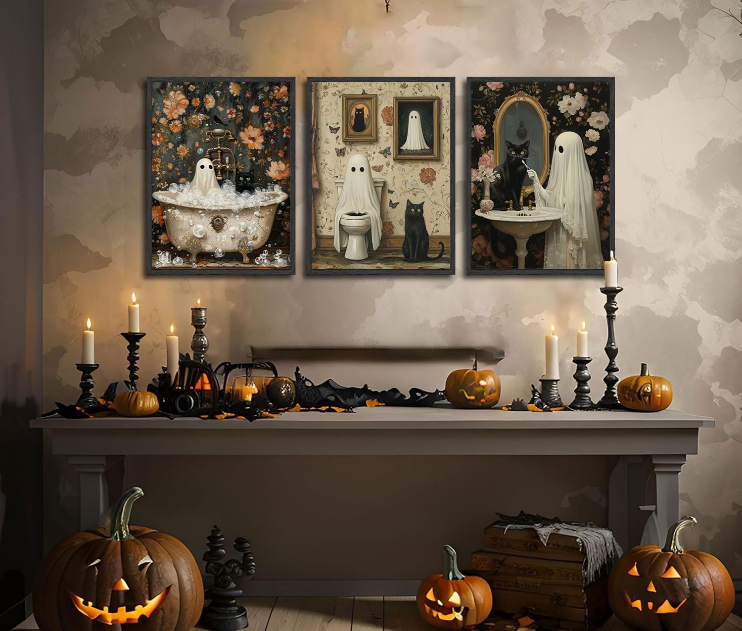 Three Halloween-themed canvas art prints featuring ghosts and black cats in bathroom scenes, displayed above a mantelpiece with pumpkins and candles.