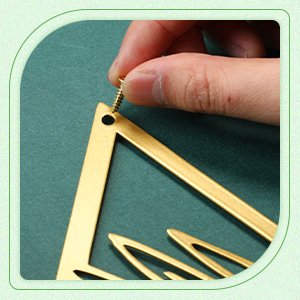 Hand screwing a metal flower wall decor piece onto a green surface