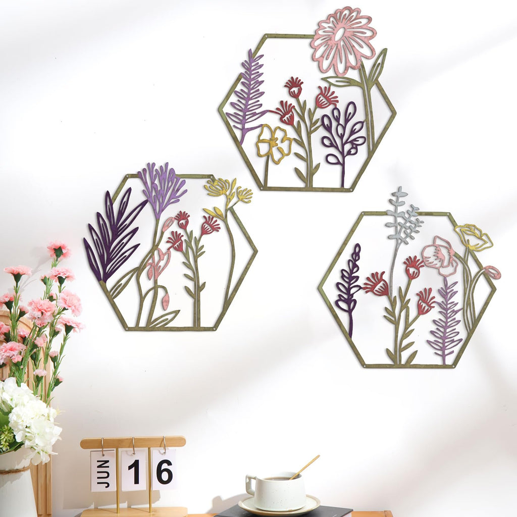 Three hexagonal metal wall art pieces featuring colorful floral and botanical designs, displayed on a white wall.