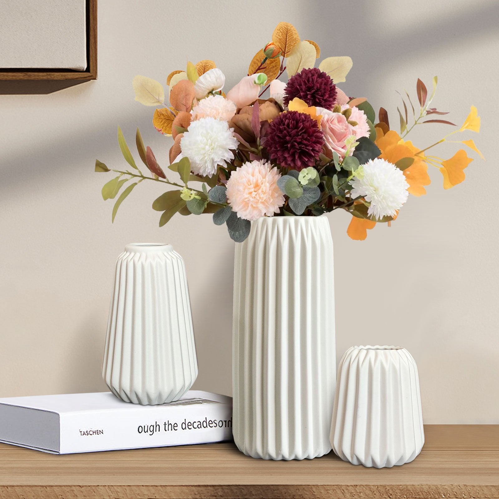 Three white ceramic vases with ribbed texture, one holding a bouquet of artificial flowers, on a wooden shelf.