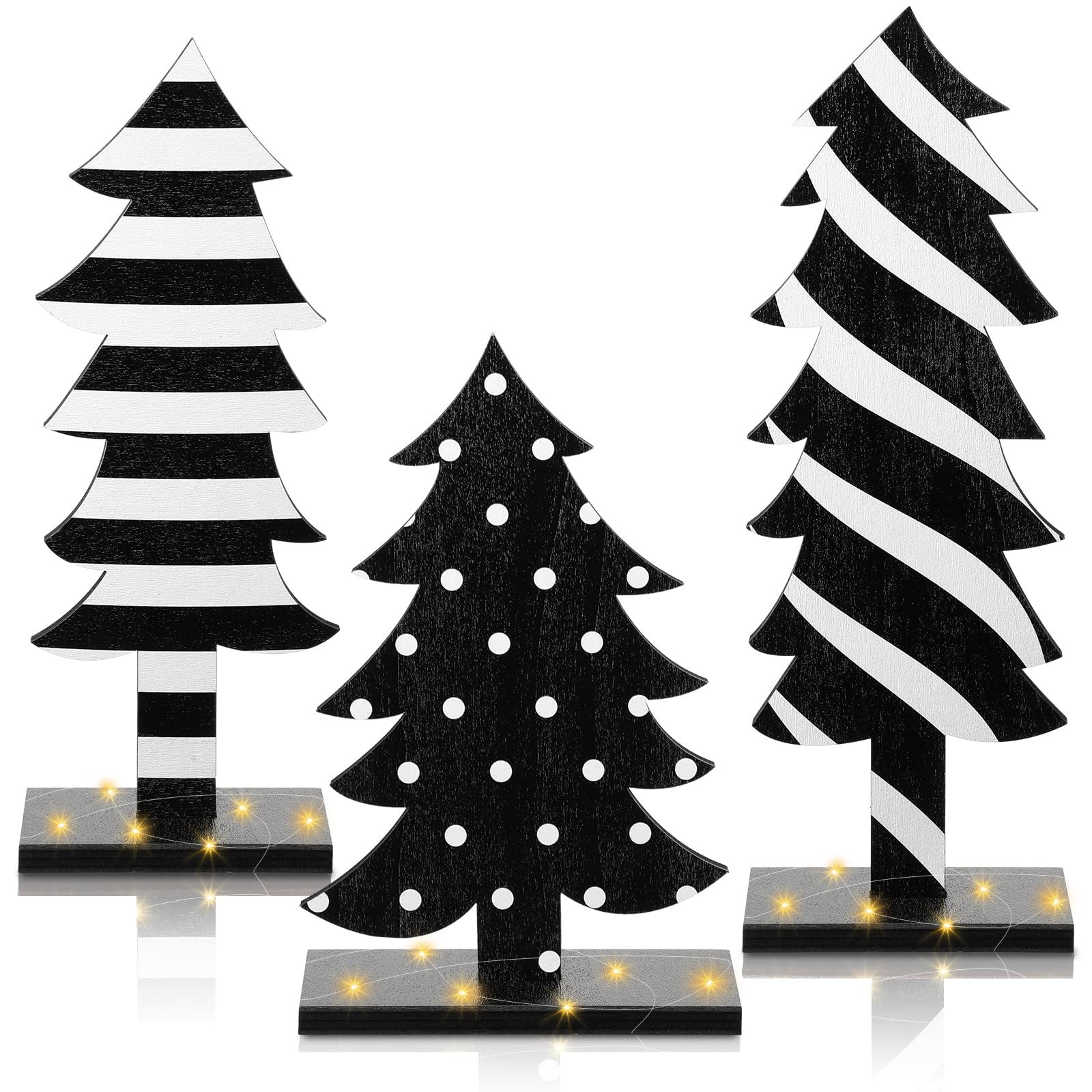 Three black and white wooden Christmas trees with bases and string lights, one with polka dots, two with stripes.