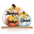 Three wooden pumpkins decorated with bows and autumn leaves, spelling "Thankful", "Grateful", and "Blessed".