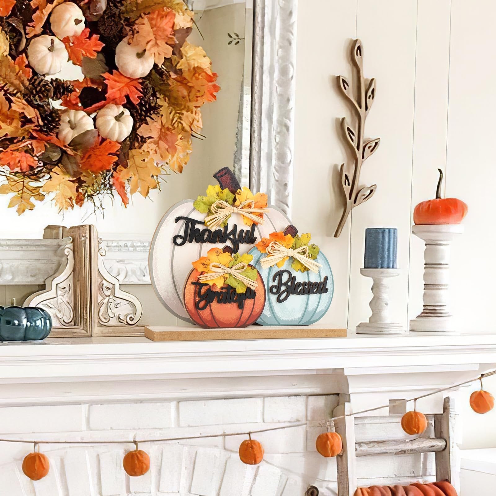 Three wooden pumpkins with fall-themed words 'Thankful', 'Grateful', and 'Blessed' displayed on a mantelpiece.