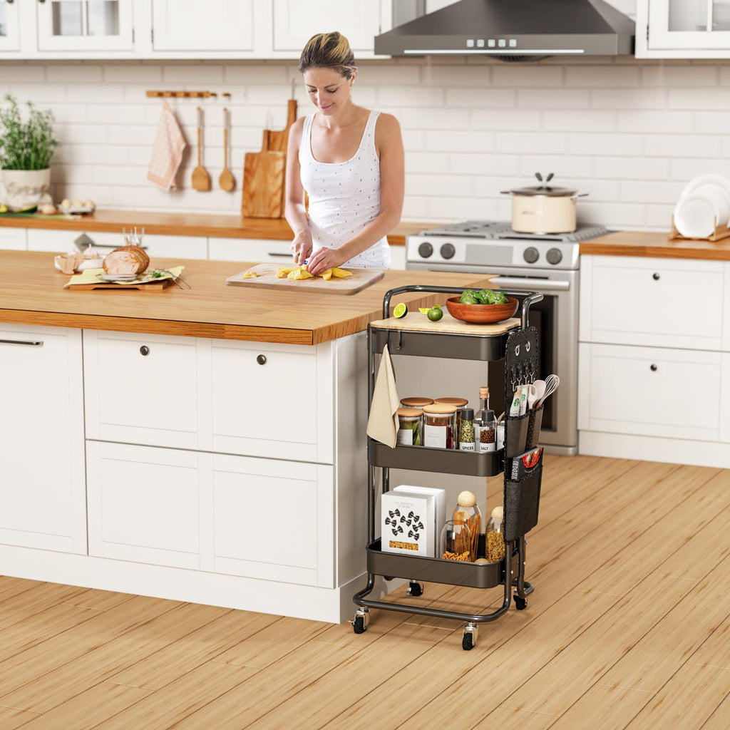 Woman preparing food in a kitchen next to a black three-tier rolling cart filled with groceries and kitchenware.