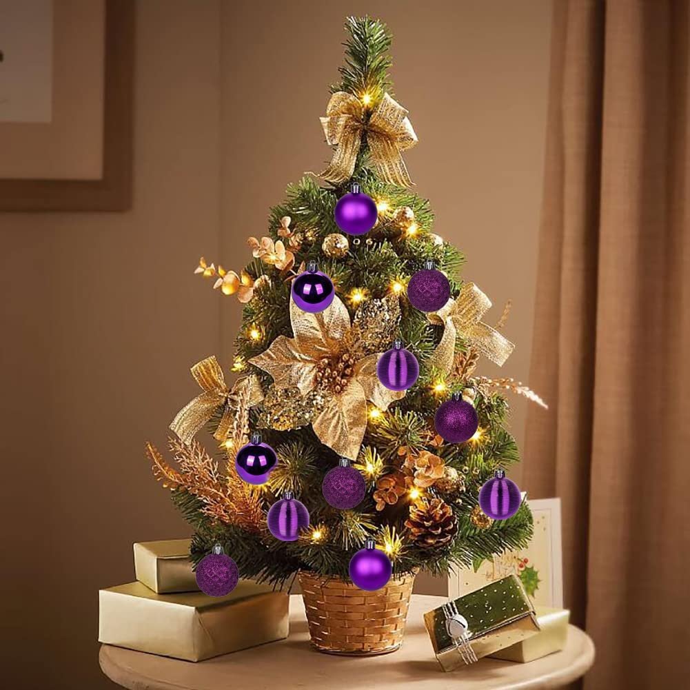 Miniature Christmas tree decorated with purple shatterproof ornaments and gold accents, surrounded by gift boxes.