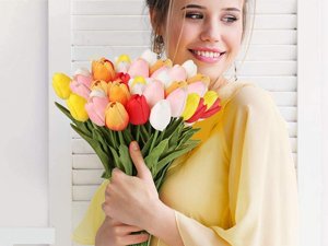 Woman in yellow dress holding a large bouquet of colorful artificial tulips