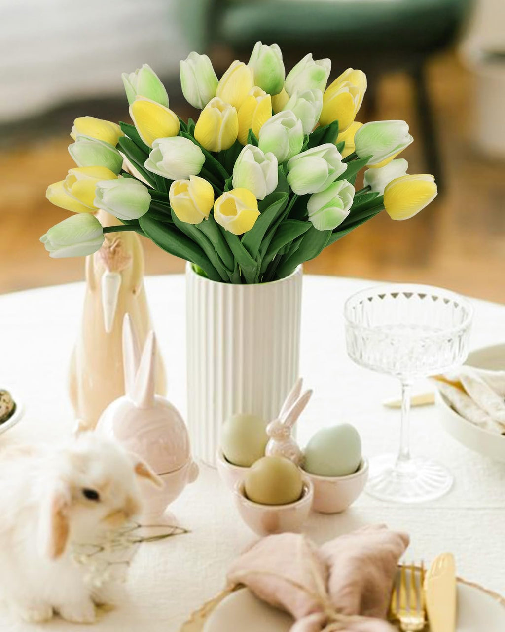 Bouquet of artificial yellow and green tulips in a white vase on a table with Easter decor