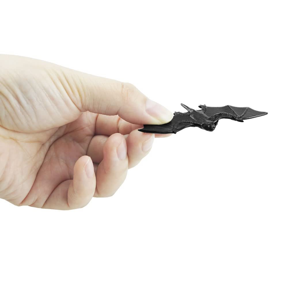 Hand holding a small black 3D plastic bat decoration against a white background.