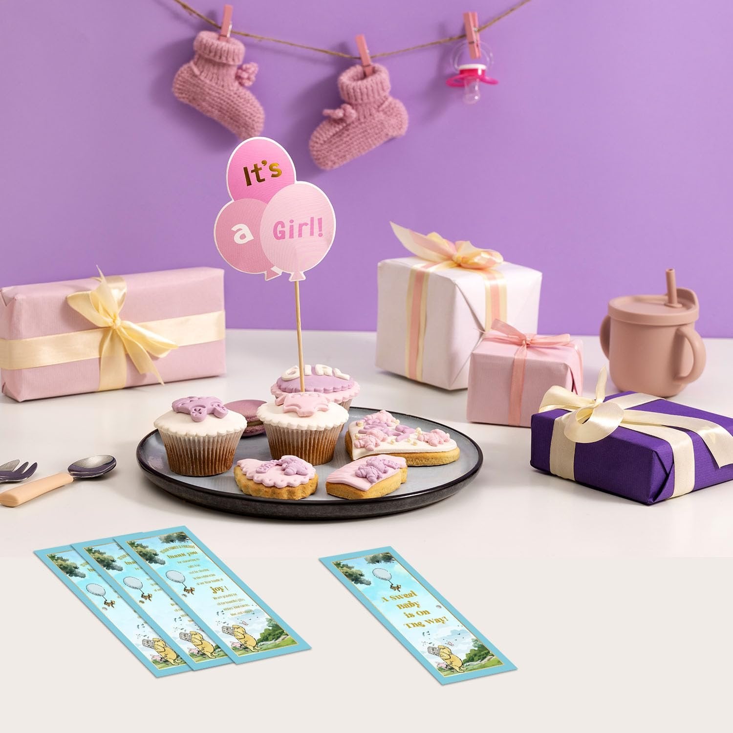 Baby shower celebration setup with cupcakes, cookies, gifts, and baby socks hanging on a line.