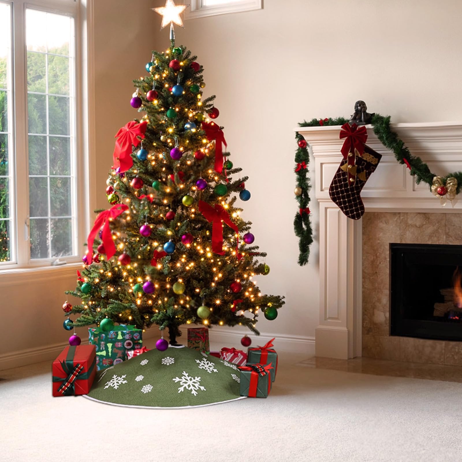 Decorated Christmas tree with presents and a green tree skirt with white snowflakes, next to a fireplace.