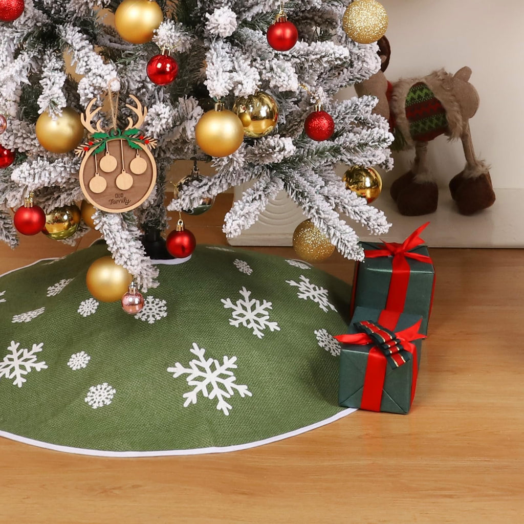 Green burlap Christmas tree skirt with white snowflake print, shown around a decorated tree with gifts.