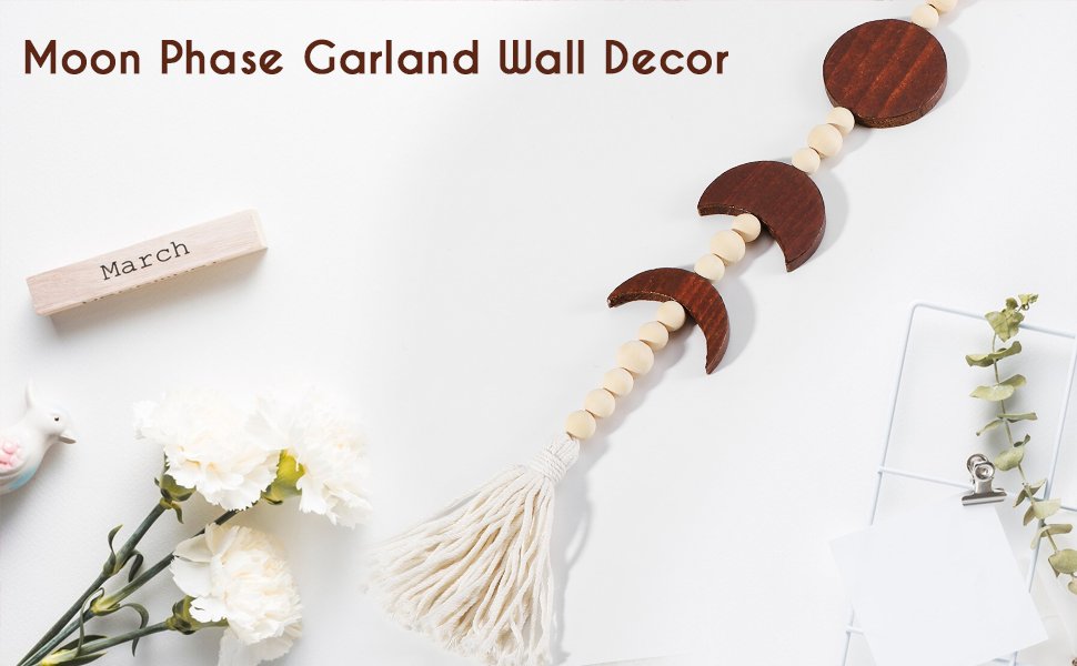 Wooden moon phase garland wall decor with beads and tassel, styled with flowers and a calendar block.