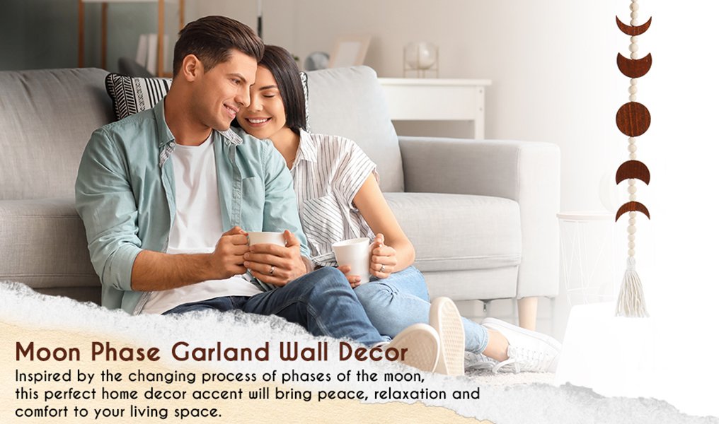 Couple sitting on floor with mugs, moon phase wall hanging decor visible on right