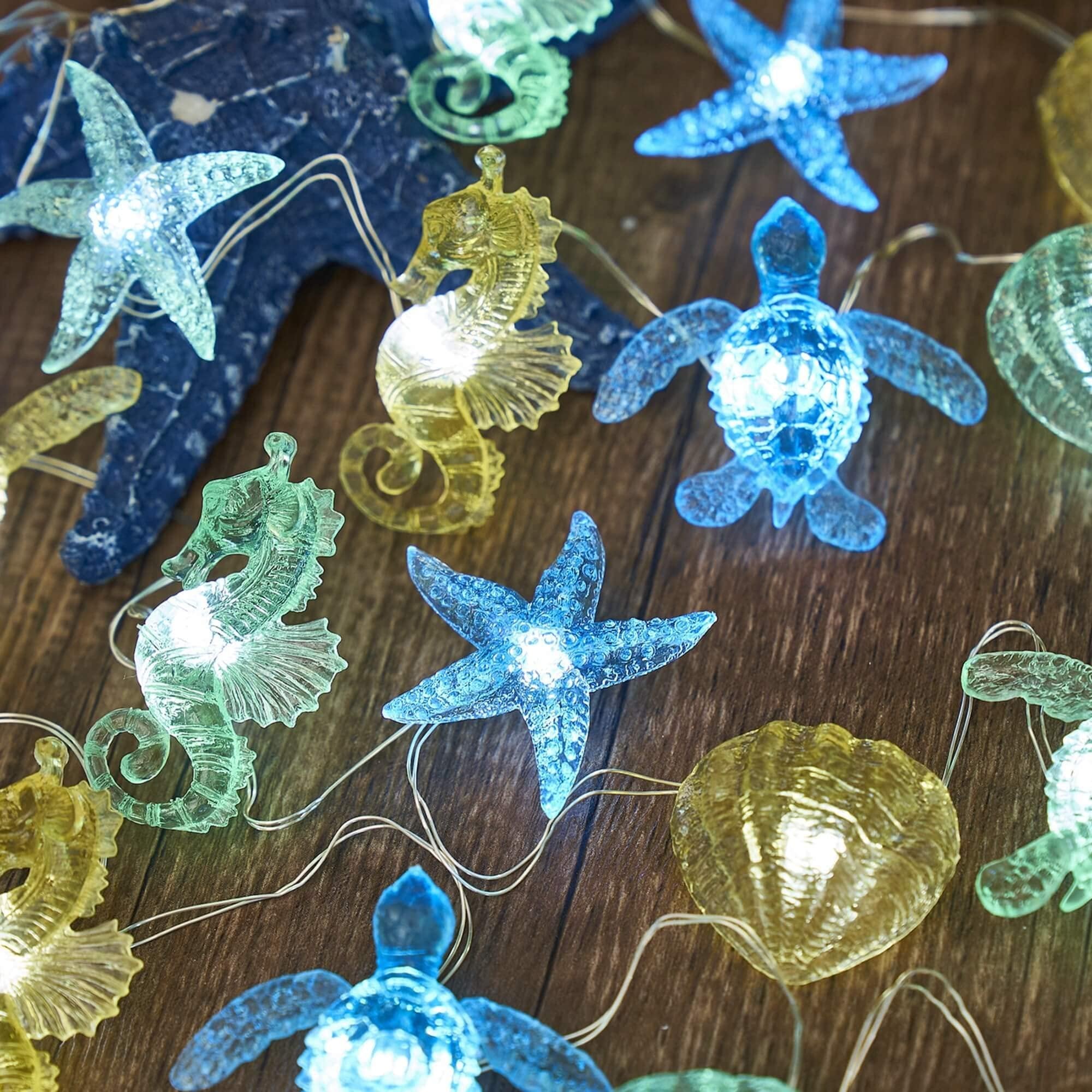 Close-up of battery-operated string lights with sea turtle, seahorse, starfish, and shell figurines on a wooden surface.