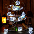 String lights with 30 small disco balls displayed on a tiered dessert stand with pastries and cookies.