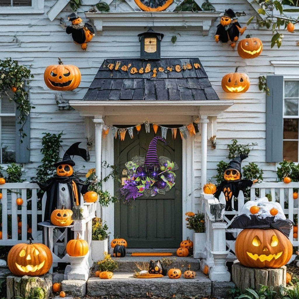 Halloween decorated house entrance with pumpkins, scarecrows, and a witch hat wreath on the door