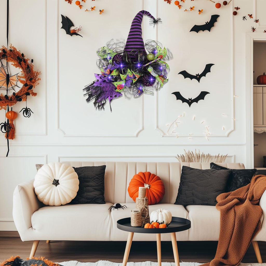 Halloween witch hat wreath with purple lights and mesh decor hanging on a wall above a sofa with pumpkins and pillows.