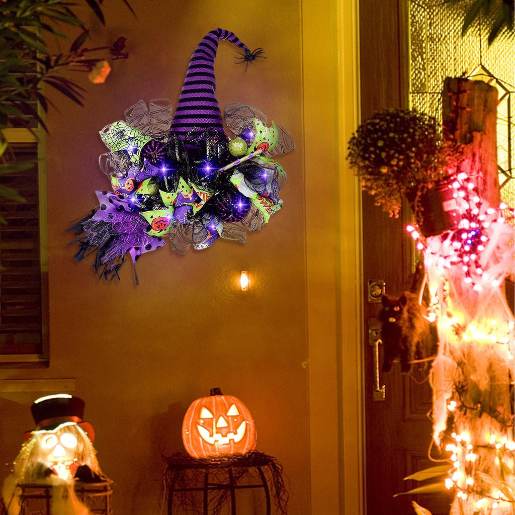 Halloween witch hat wreath with purple lights and mesh decor hanging on a wall next to a front door with decorations.