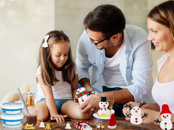 Family crafting air dry clay snowmen for Christmas activities, with clay tubs and accessories on table.