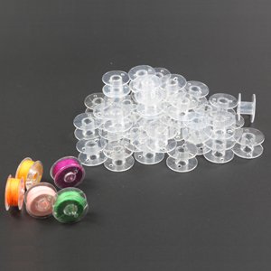 Pile of transparent plastic sewing machine bobbins with four spools of thread on the side