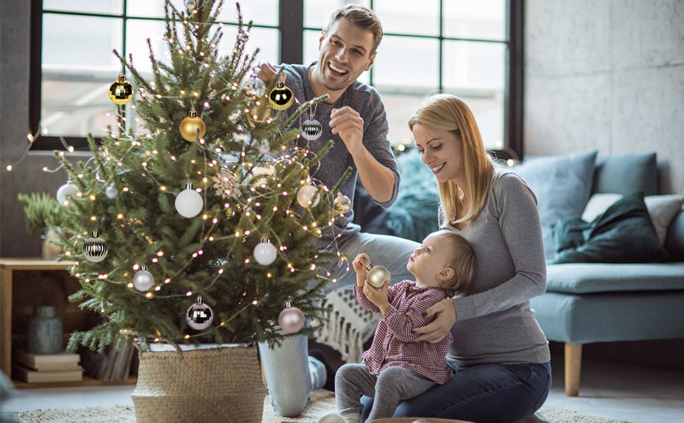 Family decorating a Christmas tree with champagne shatterproof ornaments