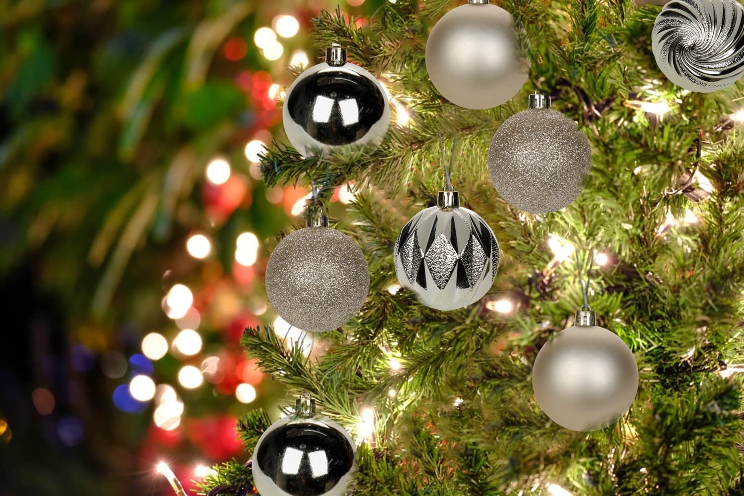 Champagne shatterproof Christmas ball ornaments hanging on a decorated tree with lights