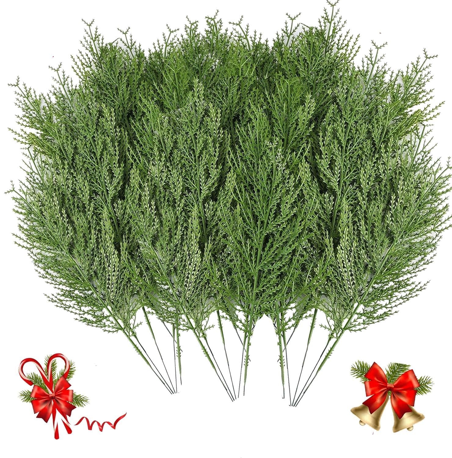 Bundle of artificial green cypress pine branches with red ribbon candy canes and bells on white background