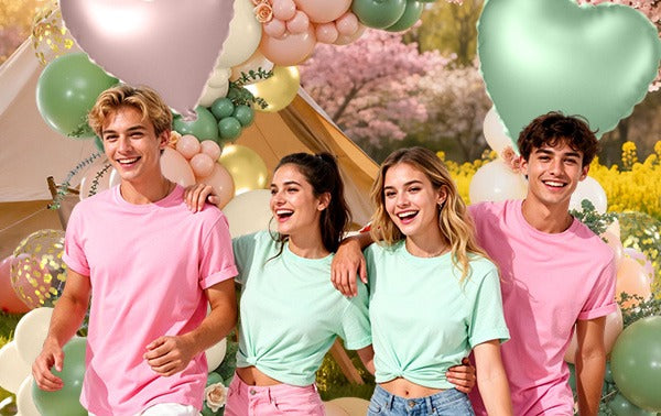 Four young adults smiling in front of a balloon arch with heart-shaped balloons and a tent.