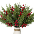 Artificial pine branches with red berries in a vase, close-up view