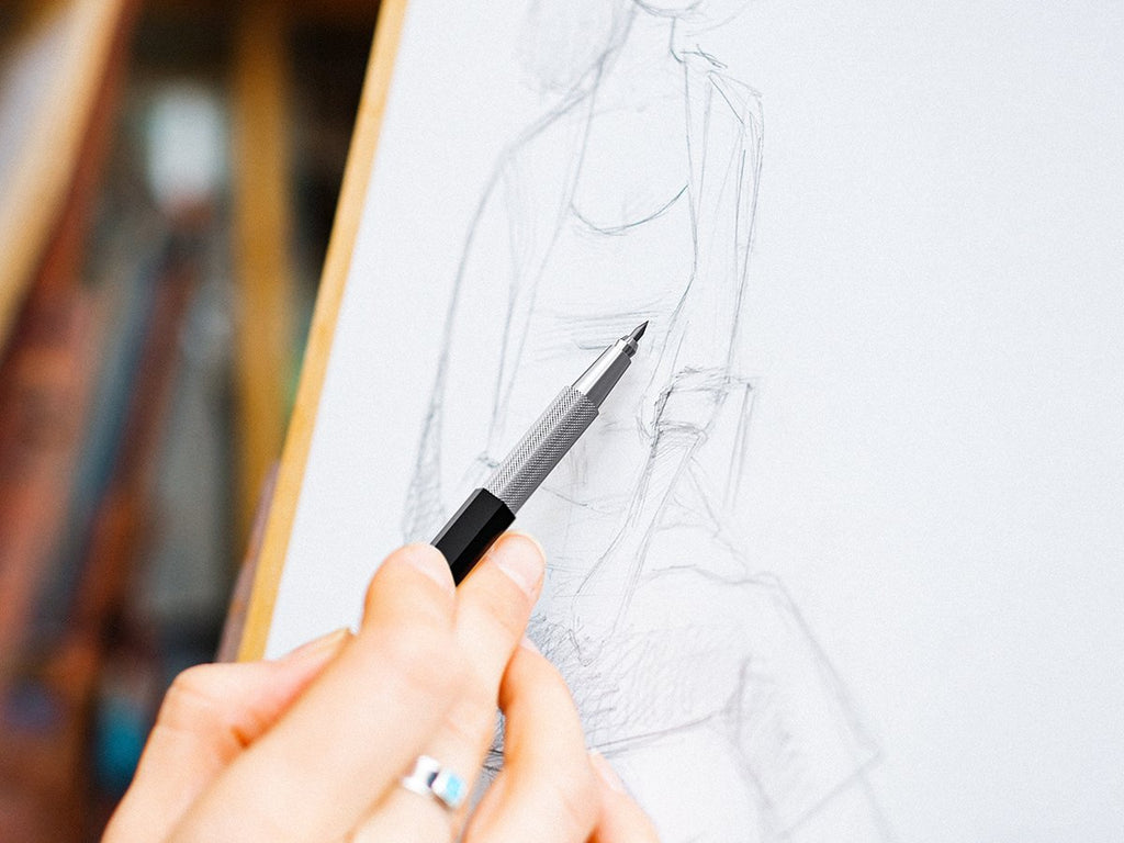Close-up of a hand holding a mechanical pencil and sketching on a pad of paper.