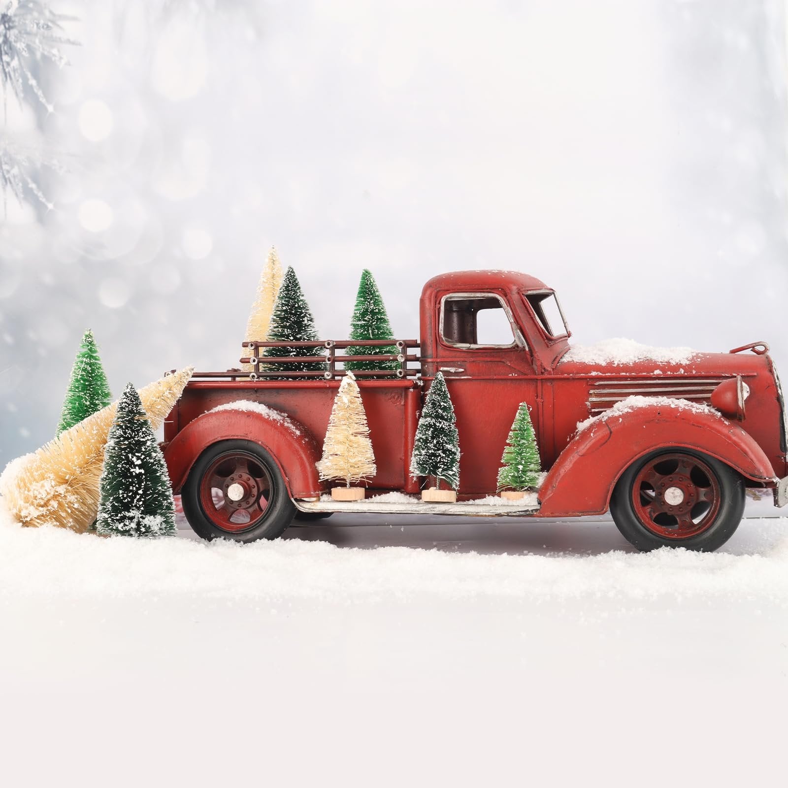 Red vintage truck carrying miniature snowy bottle brush Christmas trees in a winter scene