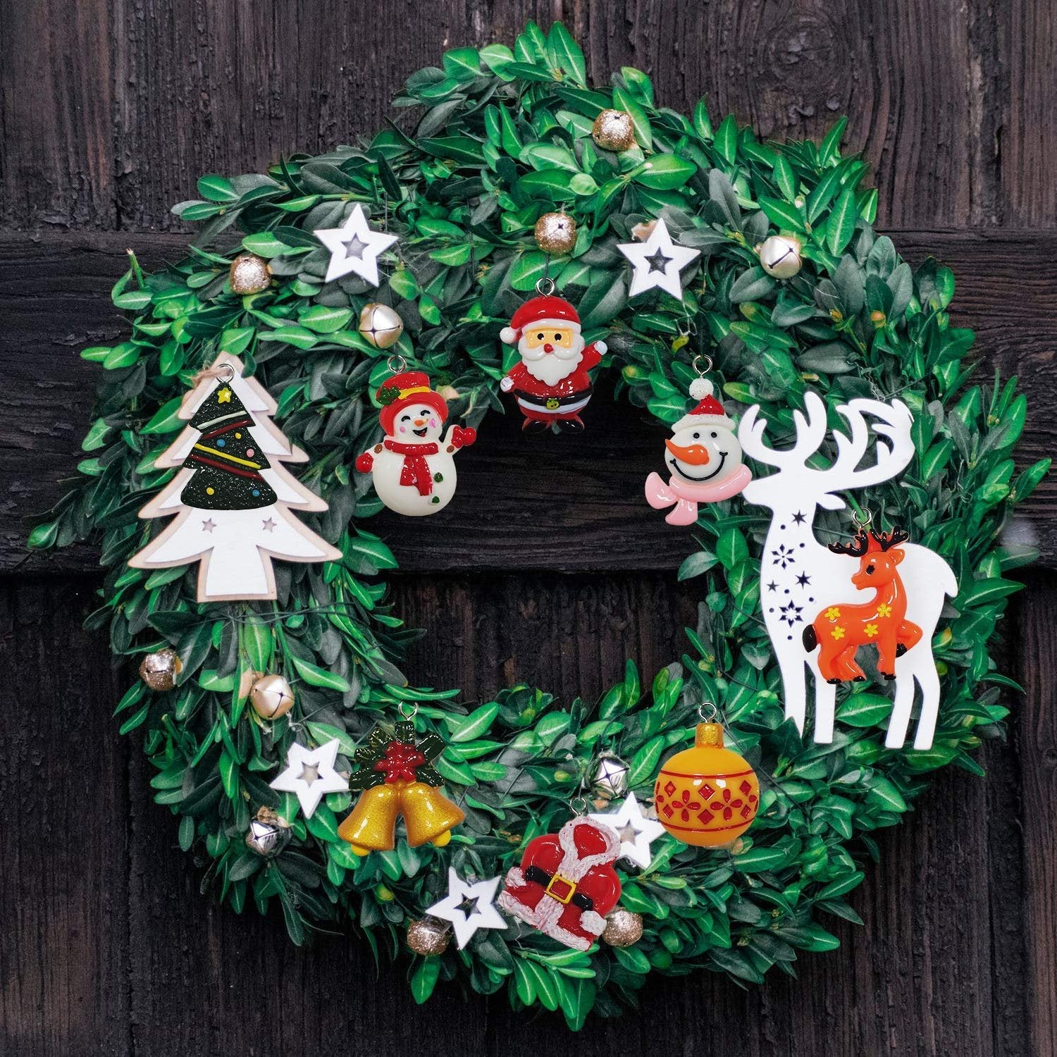 Christmas wreath with assorted mini ornaments including Santa, snowman, reindeer, and Christmas tree, hanging on a dark wooden door.
