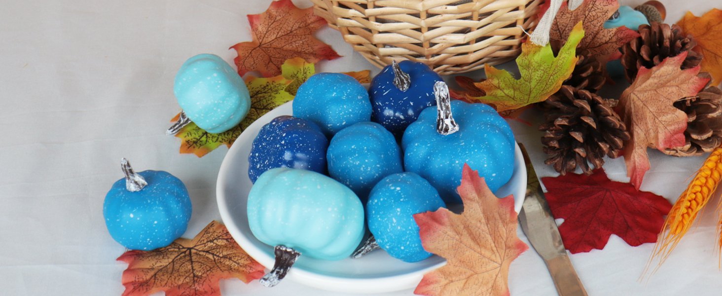 Assorted blue mini pumpkins with white speckles arranged with fall leaves and pinecones in a basket.