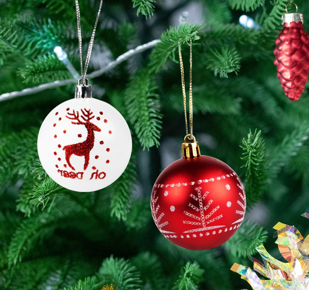 Two Christmas ball ornaments, one white with a red glitter reindeer and dots, the other red with white snowflake patterns, hanging on a Christmas tree.