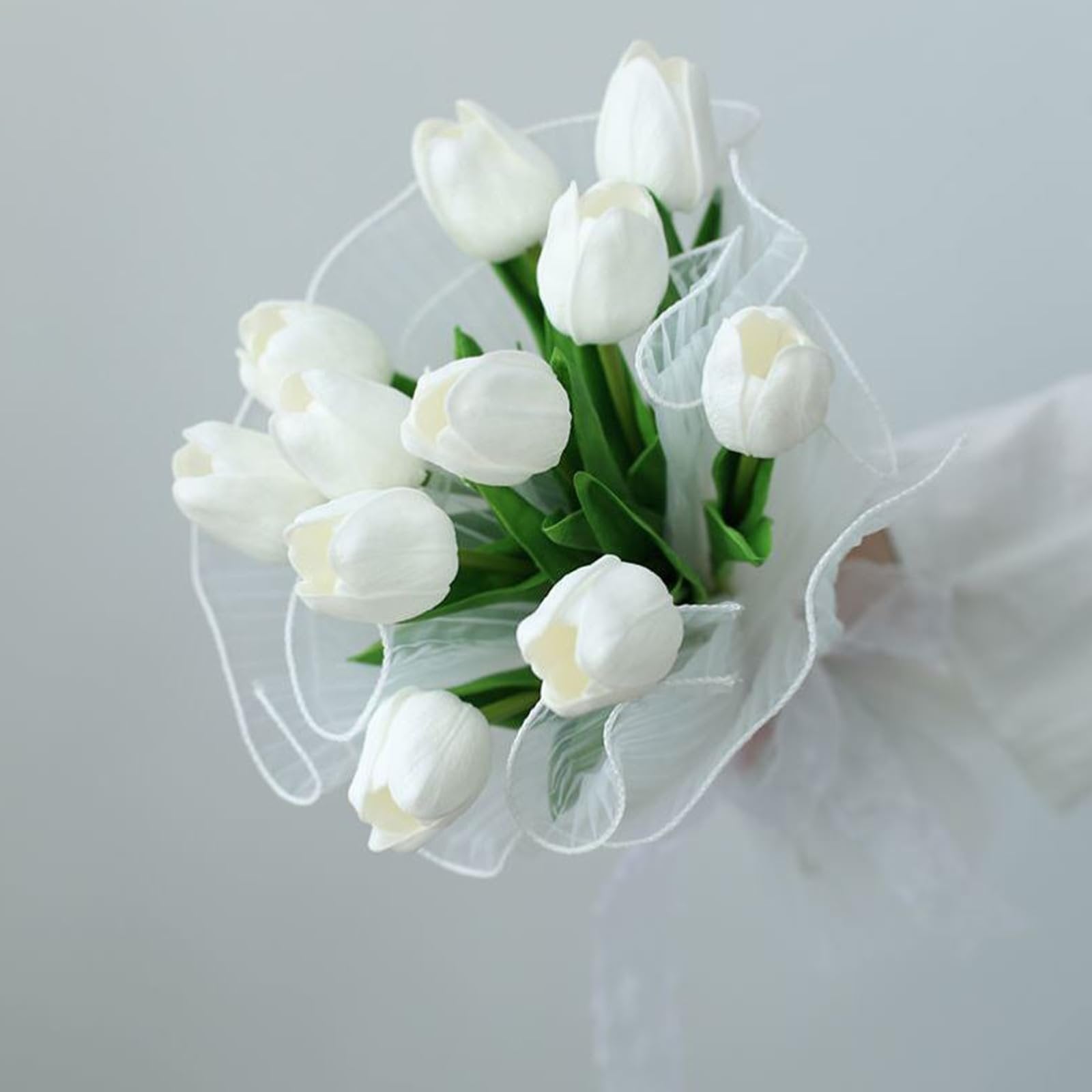 Bouquet of white artificial tulips with green leaves wrapped in sheer white ribbon