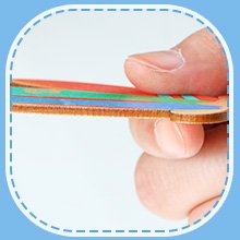 Close-up of a hand holding a layered wooden ornament with colorful painted edges.