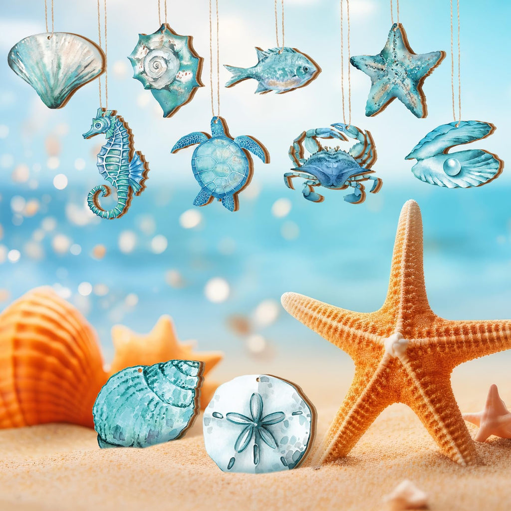Collection of 30 wooden summer ocean animal ornaments including a seahorse, turtle, crab, fish, starfish, shells, and a pearl in an oyster, displayed on a sandy beach with a blurred ocean background.