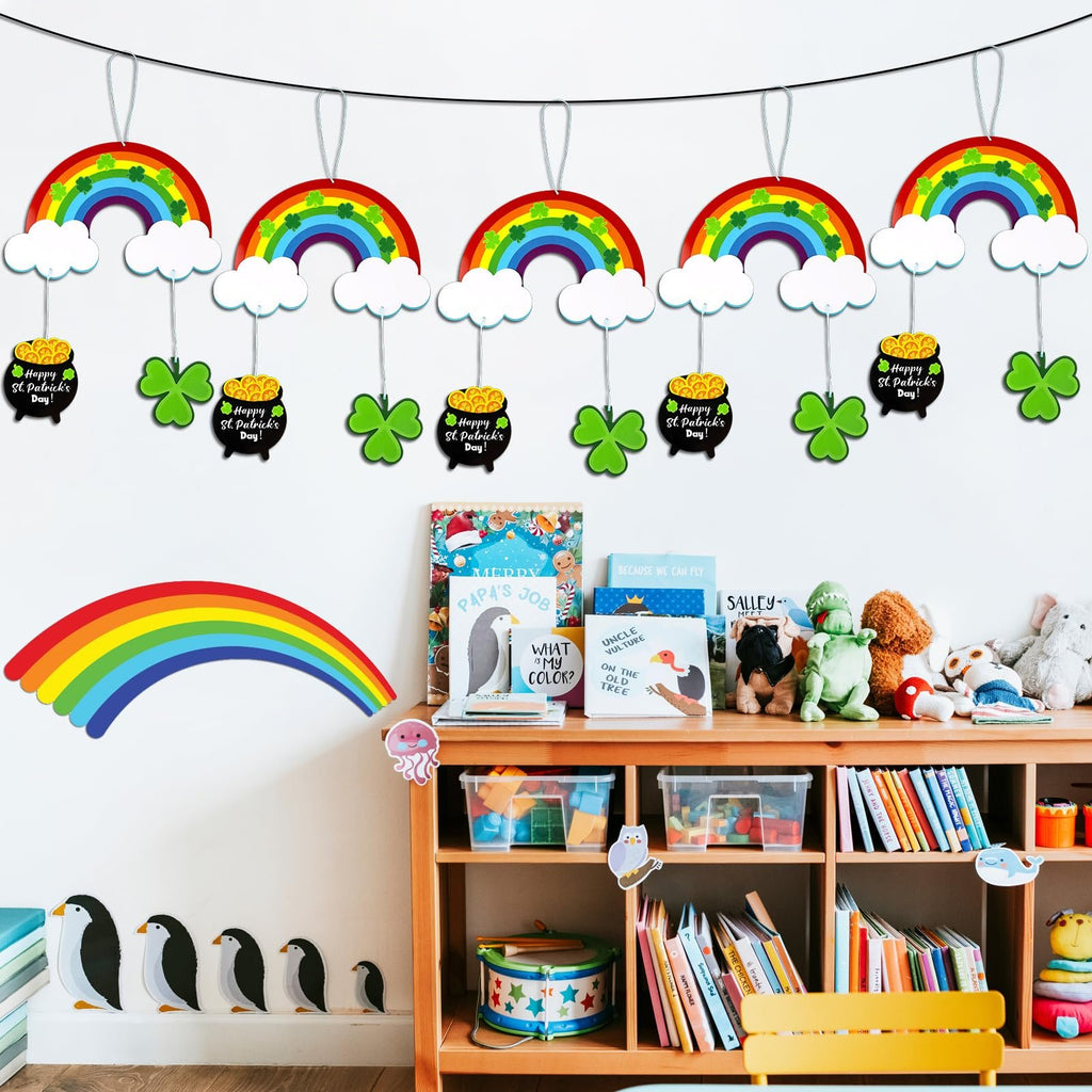 St. Patrick's Day hanging ornaments with rainbows, clouds, pots of gold, and shamrocks displayed on a wall above a bookshelf.
