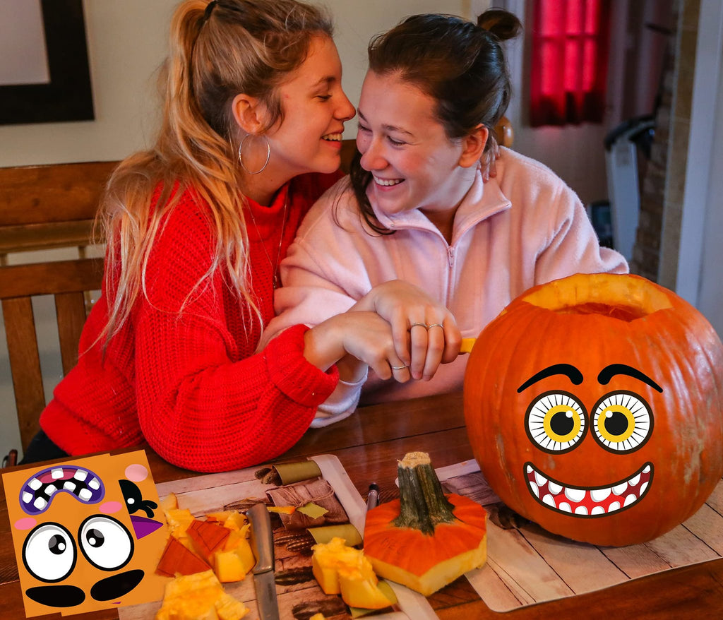 Two smiling young women carving a pumpkin with Halloween face stickers on a table with pumpkin guts and tools.