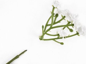 Artificial baby's breath flower stems with white blossoms on a white background