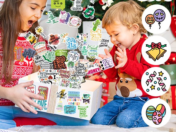 Two children excitedly opening a gift box filled with inspirational quote stickers, with holiday decorations in the background.