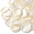 Pile of ivory silk rose petals scattered on a white background, close-up view.