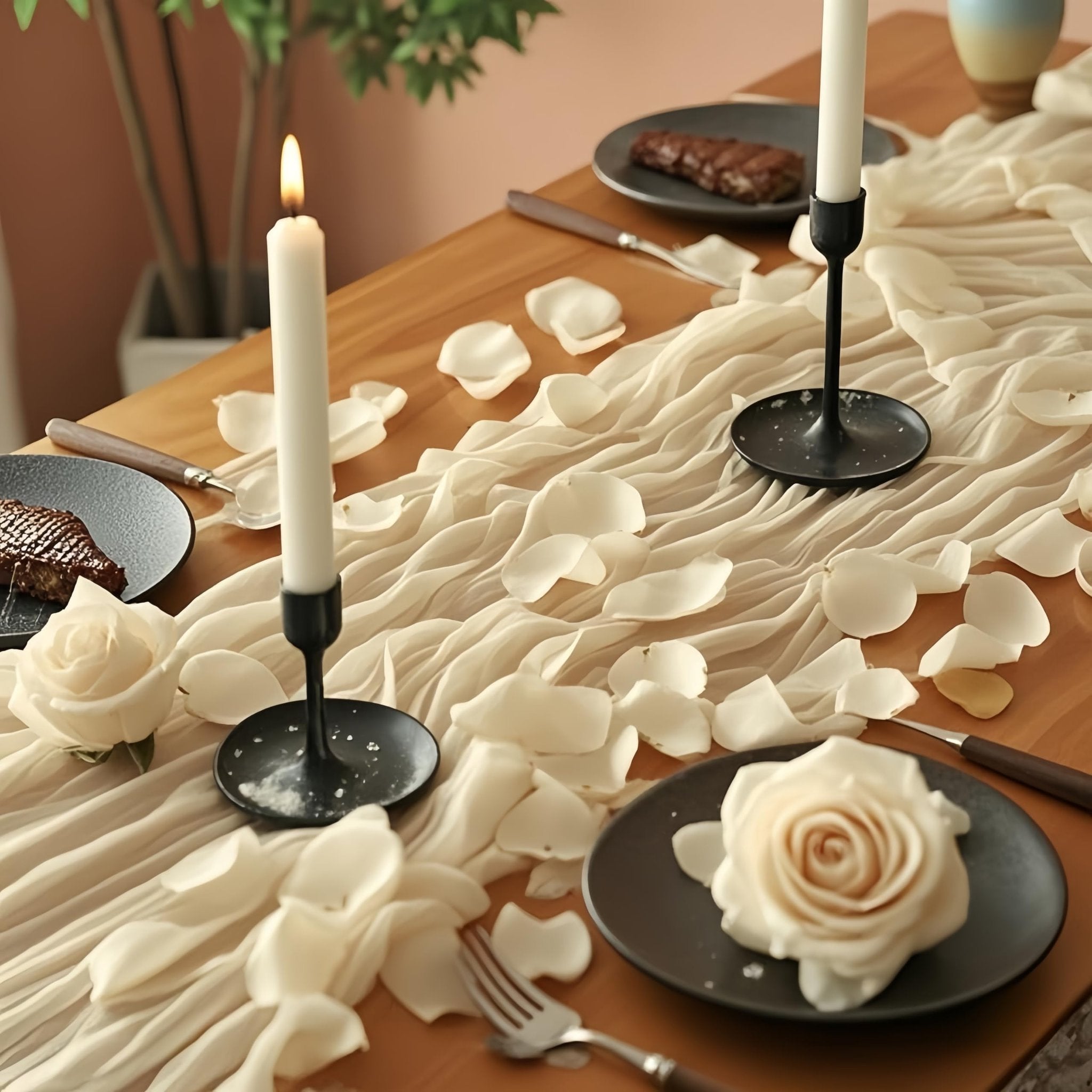 Ivory rose petals scattered on a wooden table with candles and plates of food